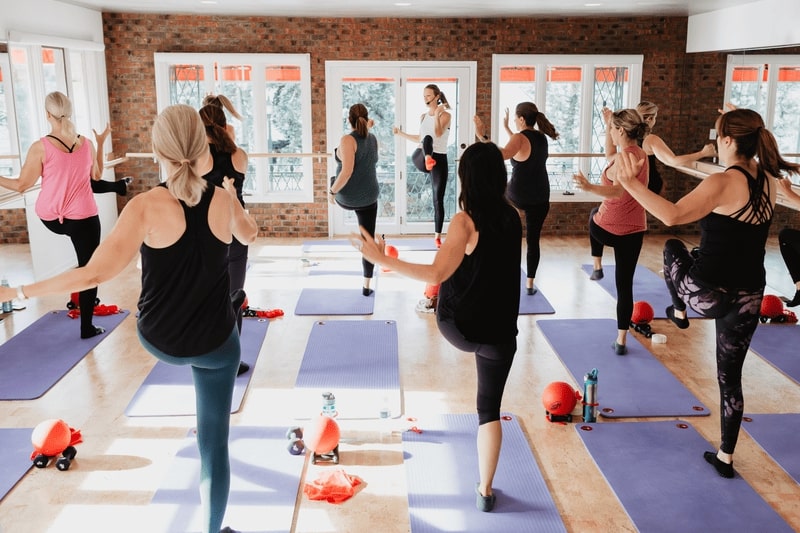 A group workout session with the instructor leading in the front, as participants follow along with standing crunches, engaging their core muscles.