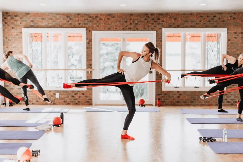 The instructor leading a class using straps, guiding participants through strength and flexibility exercises.
